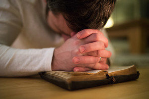 man-kneeling-in-worship over Bible