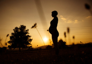 Silhouette of pregnant woman in the sunset