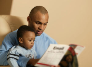 father reading a book to his son